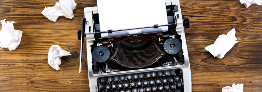 macchina da scrivere con fogli sul tavolo accartocciati