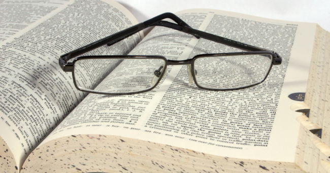 dizionario aperto con occhiali appoggiati sopra