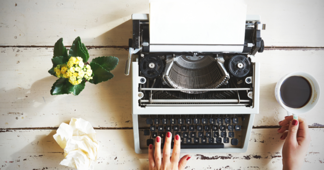 scrivere con la macchina da scrivere su un tavolo bianco con tazzina di caffè e fiori